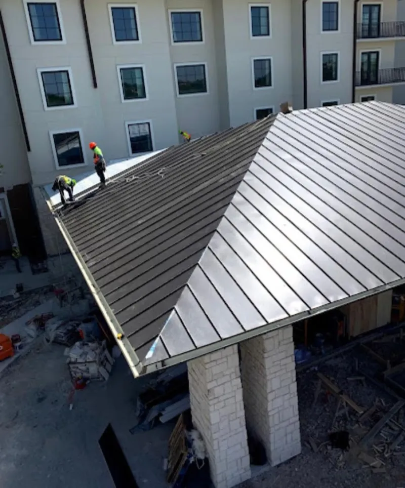Crew installing standing seam metal roof panels on a commercial project in Troutdale